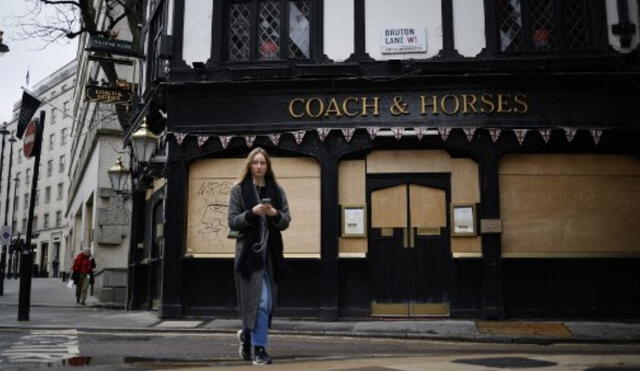 Un peatón pasa por un pub cerrado con tablas en el área de Mayfair, en el centro de Londres. Foto: AFP