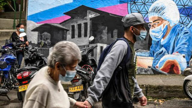 La gente pasa junto a un mural relacionado con la pandemia del coronavirus en Colombia. Foto: AFP