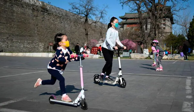 Niños con mascarilla juegan en un parque de Wuhan, China. Foto: AFP