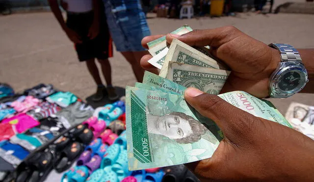 En Venezuela cada vez es mayor el número de personas que portan dólares para sus compras. Foto: AFP