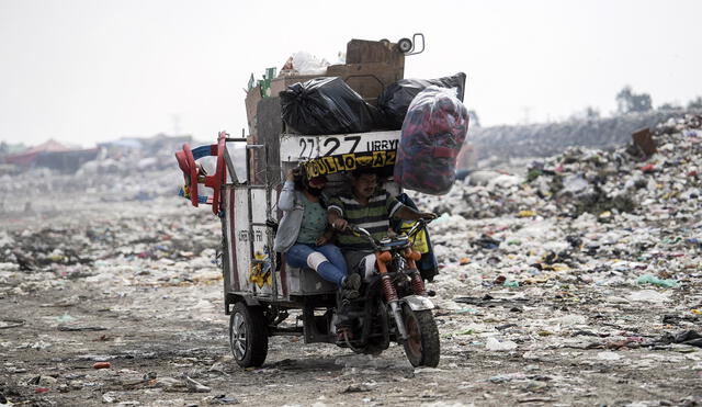 A couple ride a motor tricycle at the "Bordo de Xochiaca" garbage dump in Ciudad Nezahualcoyotl, Mexico State on July 21, 2020, amid the new coronavirus pandemic. (Photo by PEDRO PARDO / AFP)