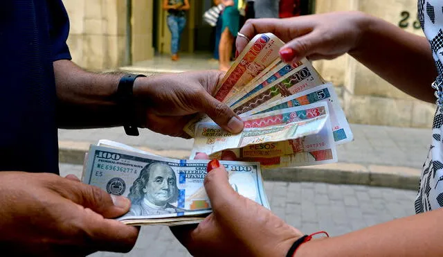 Un hombre y una mujer cambian peso convertible (CUC) y billetes de dólar en una calle de La Habana, el 10 de diciembre de 2019. Foto: AFP