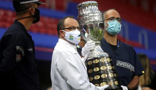 Trabajadores sanitarios cargan la Copa América previo al partido inaugural en el estadio Mané Garrincha de Brasilia. Foto: EFE/ Fernando Bizerra