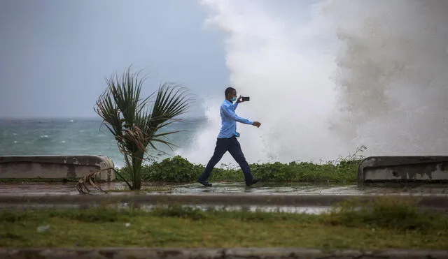 Un hombre graba un video del fuerte oleaje durante el paso de la tormenta Elsa en el Malecón de Santo Domingo, el 3 de julio de 2021. Foto: AFP