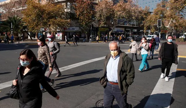 Un grupo de personas camina en Santiago después de que las autoridades sanitarias anunciaran la creación de un "carné de vacunación" para darle mayor movilidad a los inmunizados. Foto: EFE