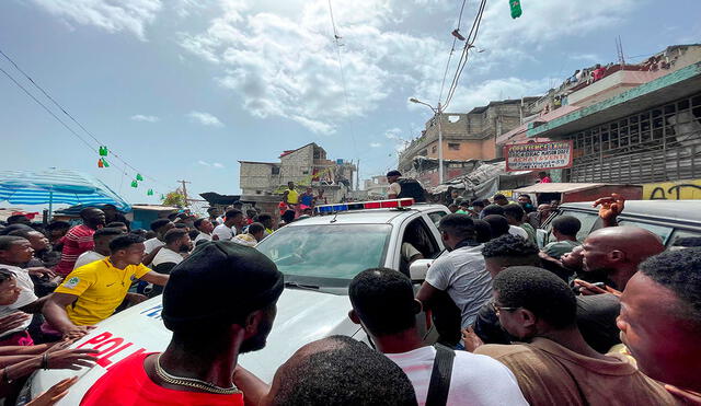 Decenas de personas se aglomeraron en torno a un automóvil de la Policía en el que había dos extranjeros capturados por un grupo de personas en Puerto Principe (Haití). Foto: EFE
