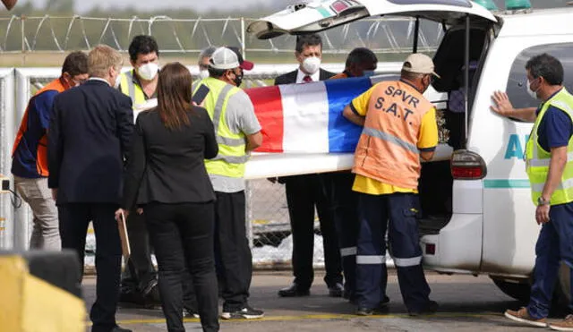 Trabajadores del aeropuerto retiran un ataúd cubierto con una bandera con los restos de Leidy Luna Villalba en Paraguay. Foto: Telemundo