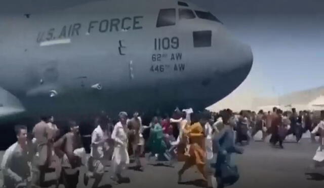En vídeos en redes sociales que se hicieron virales se ve a decenas de personas corriendo por las pistas de aterrizaje del aeropuerto de Kabul mientras un avión estadounidense se mueve, con algunas personas enganchadas a él. Foto: captura de EFE