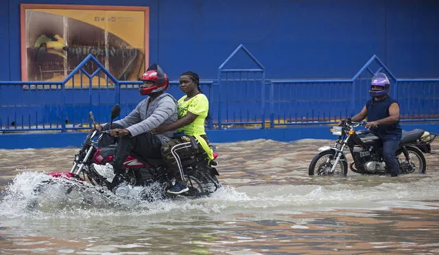 Personas se movilizan en motocicleta por una calle inundada luego del paso de la tormenta tropical Grace en Santo Domingo, República Dominicana. Foto: AFP