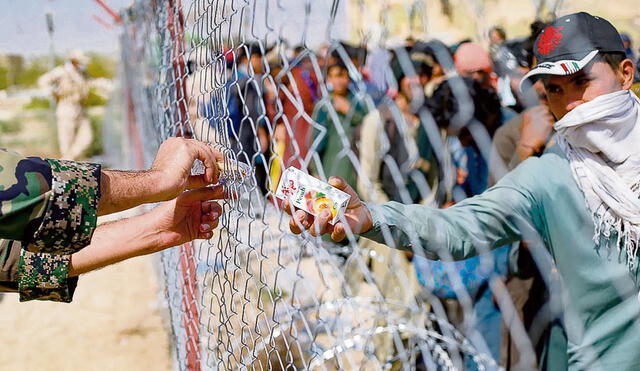 Salida. Un soldado iraní distribuye cajas de jugo a los refugiados afganos reunidos en la frontera entre Irán y Afganistán. Foto: difusión