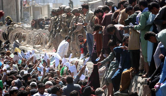 Numerosos afganos en las afueras del aeopuerto de Kabul muestran credenciales mientras intentan contactar con las fuerzas internacionales para intentar huir del país. Foto. EFE