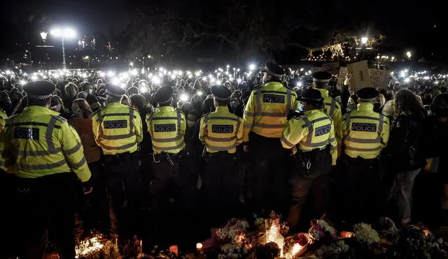 Las linternas de los teléfonos brillan en señal de protesta mientras los agentes de policía hacen guardia durante la vigilia en Londres. Foto: New York Times