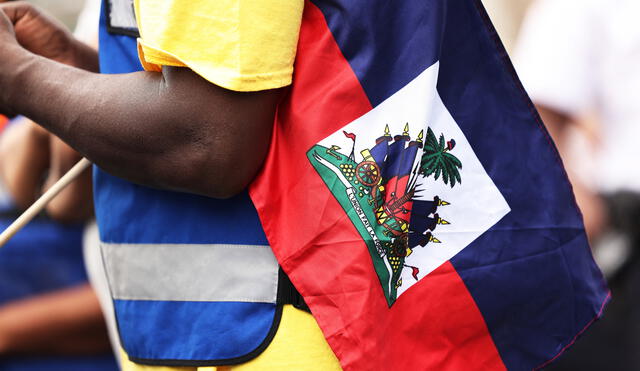 Un hombre sostiene una bandera haitiana durante una vigilia de fe. Foto: Michael M. Santiago/AFP/referencial