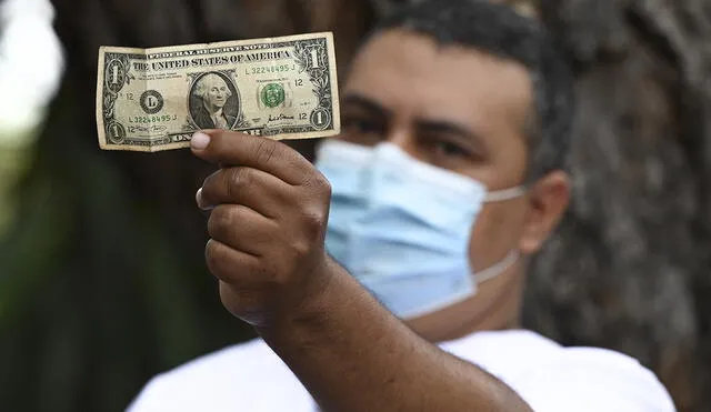 Un enfermero en Venezuela muestra un dólar, según él, es el equivalente a dos semanas de salario por su trabajo. Foto. AFP