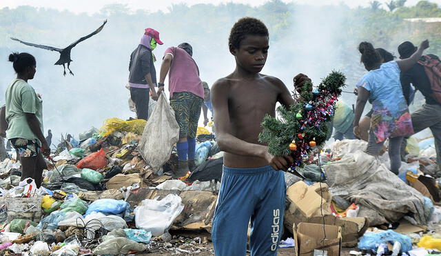 Gabriel sostiene una decoración navideña que encontró mientras hurgaba en la basura en el vertedero. Foto: AFP