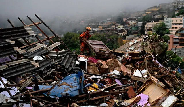 Un miembro de equipo de rescate de los servicios de bomberos levanta escombros para buscar sobrevivientes después de un deslizamiento de tierra en Petrópolis, Brasil. Foto: AFP