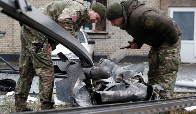 Un policía y personal de seguridad miran con atención los restos de un proyectil caído en Kiev, el 24 de febrero de 2022. Foto: AFP