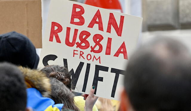Un manifestante sostiene un cartel que dice "Prohibir a Rusia de SWIFT" durante una protesta contra la invasión rusa de Ucrania. Foto: AFP