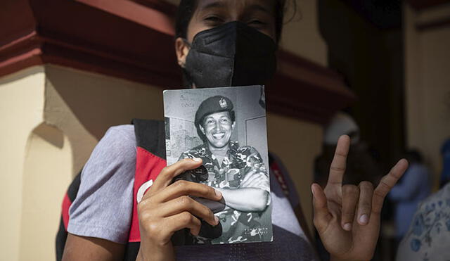 Una mujer muestra hoy una foto de Hugo Chávez durante un homenaje por los nueve años de su fallecimiento. Foto: EFE