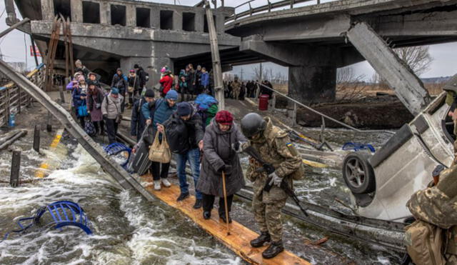 Civiles cruzan un puente destruido mientras huyen del asedio en la ciudad de Irpin, en Ucrania. Foto: EFE