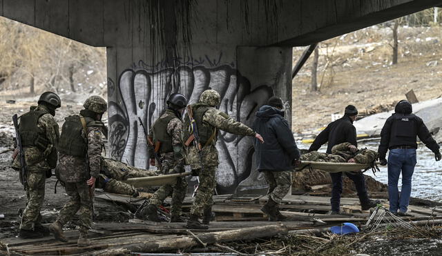 Militares ucranianos transportan el cuerpo de camaradas en camillas en la ciudad de Irpin, al noroeste de Kiev, el 13 de marzo de 2022. Foto: AFP