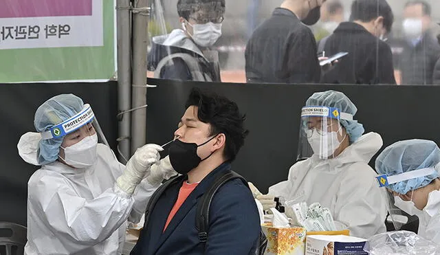 Una trabajadora de salud toma una muestra de hisopado nasal de un hombre en un centro de pruebas de coronavirus en Seúl. Foto: AFP