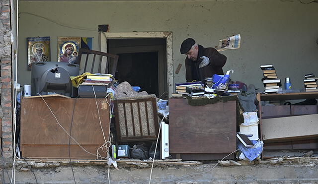 Un residente local tira una silla de oficina rota mientras recupera lo que puede de su apartamento destruido por un bombardeo ruso. Foto: AFP