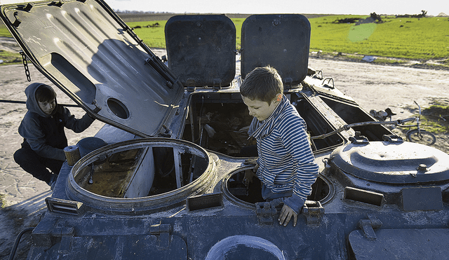 Juguemos a la guerra. Niños ucranianos juegan en los escombros de un tanque ruso. Foto: