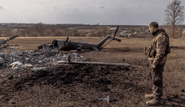 Soldado ucraniano frente a un helicóptero ruso destruido. Foto: EFE