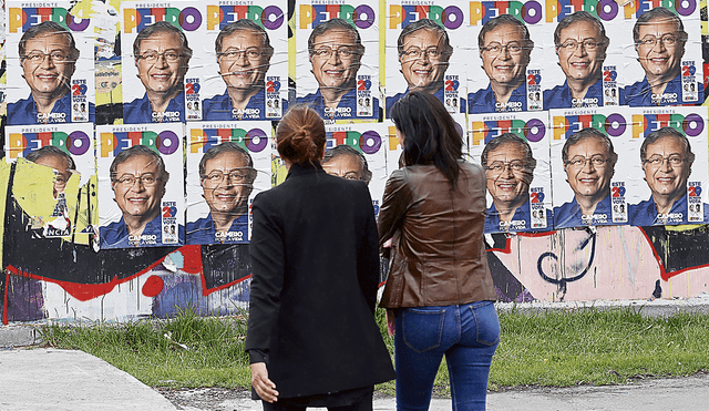 En campaña. Dos colombianas caminan cerca de volantes publicitarios del candidato presidencial Gustavo Petro, en Bogotá. Foto: EFE