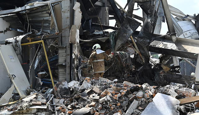 Los rescatistas limpian los escombros del centro comercial Amstor en Kremenchuk, Ucrania, un día después del ataque. Foto: AFP