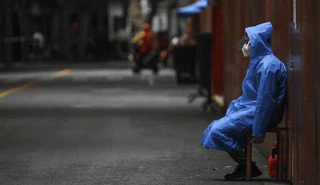Un trabajador se sienta junto a una valla erigida para cerrar una zona residencial bajo encierro de COVID-19 en Shanghái. Foto: AFP