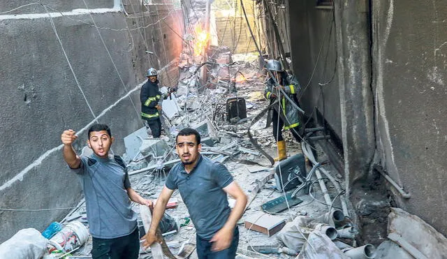 Bombardeos. Jóvenes palestinos evacúan un edificio que fue impactado por misiles israelíes. Foto: EFE