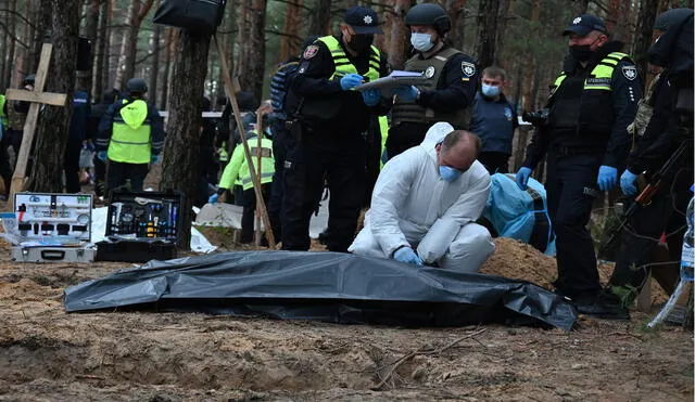 Un técnico forense cierra una bolsa para cadáveres en un bosque en las afueras de Izyum, en el este de Ucrania. Foto: AFP