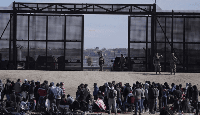 Migrantes que cruzaron la frontera de México hacia EE. UU. esperan junto al muro. Foto: AP