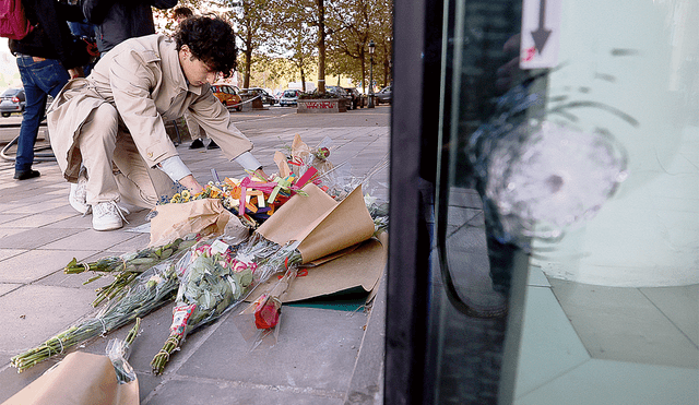 Luto en la ciudad. Un vecino deja un ramo de flores en el lugar donde asesinaron al profesor. Foto: EFE