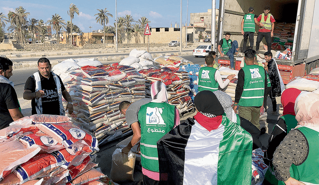 Ayuda humanitaria. Personal palestino colabora en el suministro de ayuda humanitaria en los grandes camiones de la ONU que saldrán desde Egipto. Foto: EFE