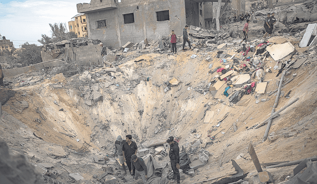 Bombardeo. Vecinos buscan restos humanos en el cráter dejado por la explosión de un misil que derrumbó un edificio en Gaza. Foto: EFE