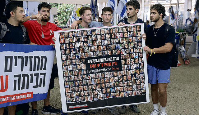 Secuestrados. Jóvenes sostienen una pancarta que muestra fotografías de personas secuestradas por militantes de Hamás. Foto: EFE