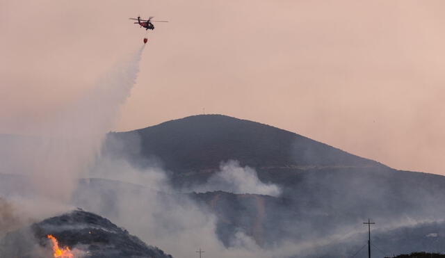 Hace dos días, un helicóptero descargó agua para combatir un incendio que afectaba la zona fronteriza en San Diego, California. Foto: AFP.