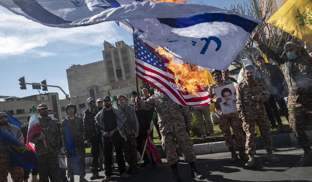 Miembros del Cuerpo de la Guardia Revolucionaria Islámica (IRGC) queman banderas israelíes y estadounidenses. Foto: CBS News   