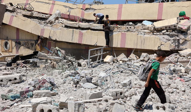 Un grupo de personas inspecciona los daños causados por un ataque israelí contra una escuela que albergaba a palestinos desplazados en el barrio de Rimal. Foto: AFP   