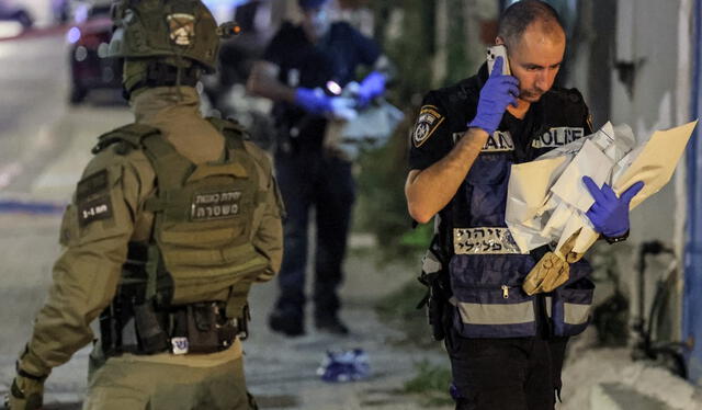  Un miembro del departamento forense de la policía israelí pasa junto a un miembro de las fuerzas especiales en el lugar de un ataque con disparos en Jaffa. Foto: AFP   