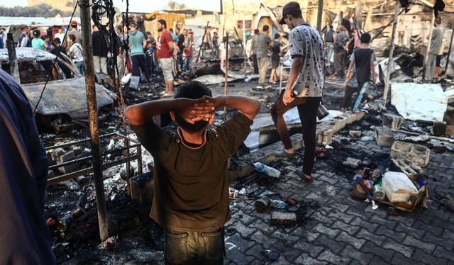 Varias personas comprueban los destrozos causados por un ataque del ejército israelí alrededor de las tiendas de campaña para personas desplazadas dentro de los muros del Hospital de los Mártires de Al-Aqsa. Foto: AFP   