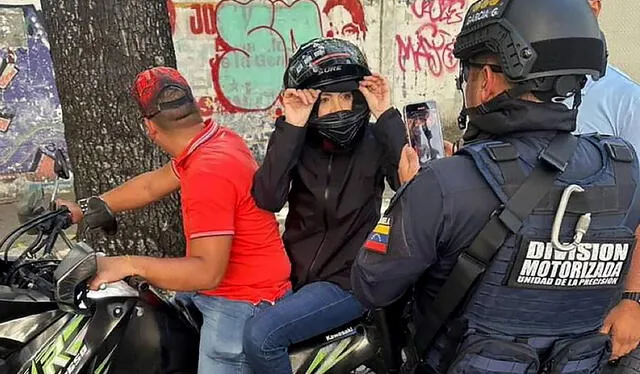 María Corina Machado siendo filmada por un agente de la Policía Nacional tras pronunciar un discurso durante una manifestación. Foto: AFP 