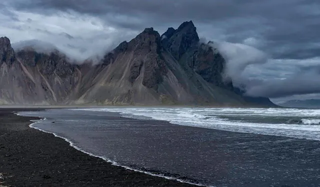 Playa de arena volcánica negra y montaña rodeada de nubes en Islandia. Foto: Raúl Demangel    
