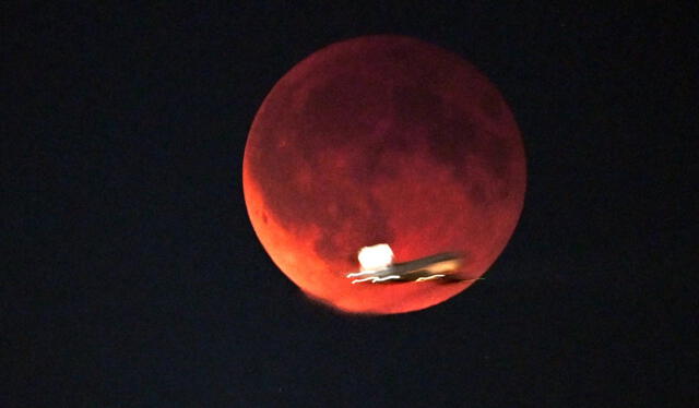  Un avión que despega pasa junto a la luna que se oscurece durante un eclipse lunar en Schoenefeld, cerca de Berlín, Alemania. Foto: AFP   