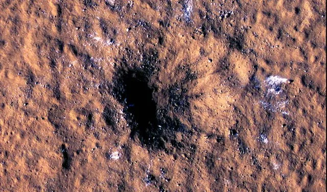 Cráter dejado por el impacto de meteorito en Marte. Se observan trozos de hielo en los alrededores. Foto: NASA