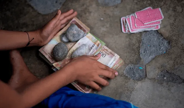 Ajiley es un juego de cartas muy popular en Venezuela al que los pequeños le han dado un giro creativo transando los premios con estos billetes inservibles. Foto: AFP