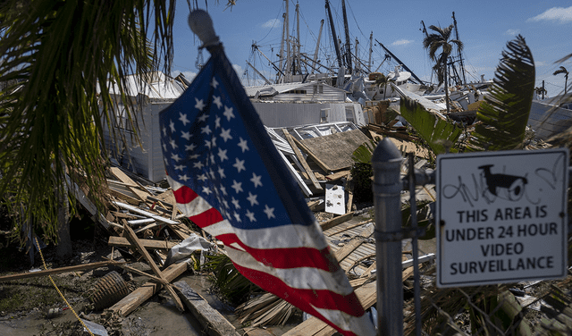 La bandera de EE. UU. ondea mientras se ve una pila de botes arrastrados por el agua en el fondo después del huracán Ian, en Fort Myers, Florida.